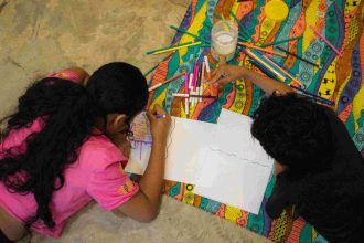Crianças desenhando juntas em evento literário.