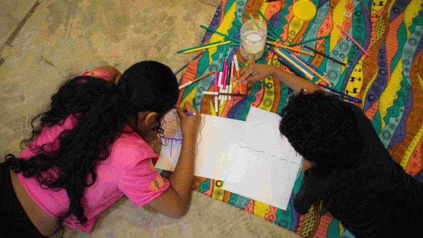 Crianças desenhando juntas em evento literário.