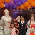Crianças e adultos fantasiados de personagens de terror em evento de Halloween.