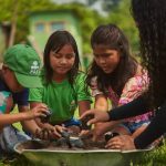 Crianças e consultora da FAS plantando em atividades educacionais no Amazonas.