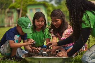 Crianças e consultora da FAS plantando em atividades educacionais no Amazonas.