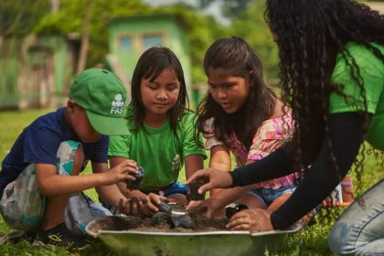 Crianças e consultora da FAS plantando em atividades educacionais no Amazonas.