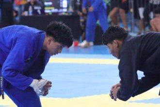 Dois atletas de jiu-jítsu se preparam para uma luta em uma competição.