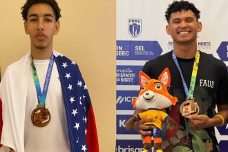 Dois jovens com medalhas em evento esportivo, um com bandeira dos EUA e outro com mascote.