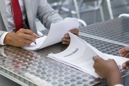 Duas pessoas analisando documentos de inventário em um escritório.