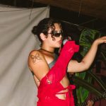 Duca Vieira cantando no palco com roupa vermelha e óculos escuros