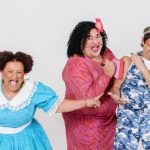 Elenco de 'Dona Batata' em apresentação teatral, com figurinos coloridos e expressões exageradas.