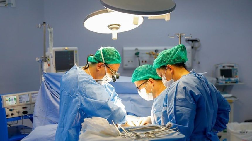 Equipe médica realiza cirurgia em centro cirúrgico, com foco em transplante de fígado.
