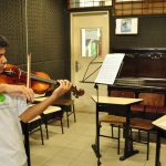 Estudante da UFAM tocando violino em sala de aula.