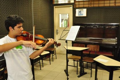 Estudante da UFAM tocando violino em sala de aula.