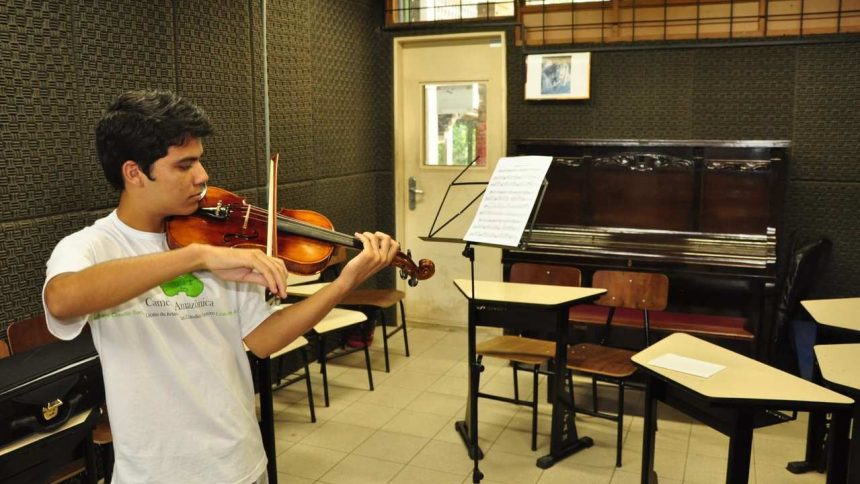 Estudante da UFAM tocando violino em sala de aula.