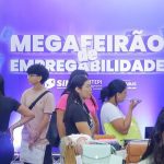 Evento Mega Feirão de Empregabilidade com pessoas em frente a um banner.