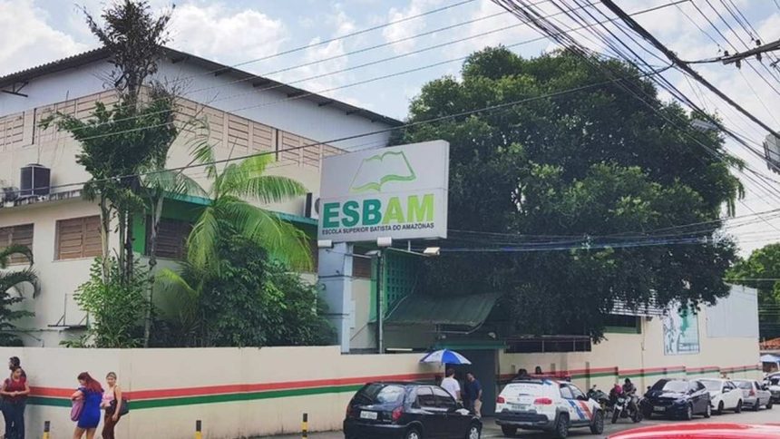 Fachada da ESBAM, escola com placa e carros estacionados na rua.