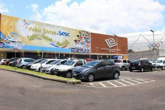 Fachada da Feira de Livros Sesc no Centro de Convenções Vasco Vasques, com carros estacionados.