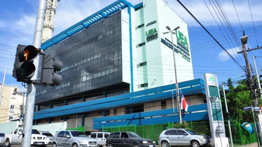 Fachada da Universidade do Estado do Amazonas (UEA) em dia ensolarado, com carros na rua e sinal de trânsito.
