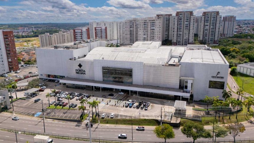 Fachada do Shopping Ponta Negra em Manaus, com prédios ao fundo e estacionamento.