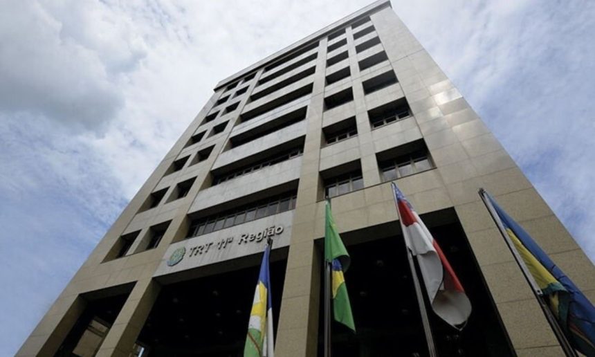 Fachada do TRT da 11ª Região, com bandeiras e céu azul.