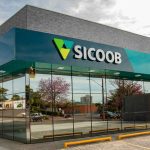 Fachada moderna da Sicoob, banco cooperativo, com logo em destaque e vidros reflexivos.