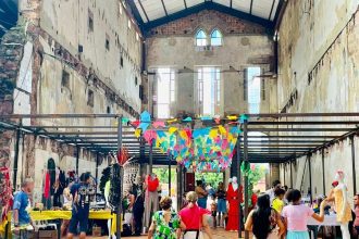 Feira criativa Caipora com pessoas e expositores em espaço com arquitetura antiga.