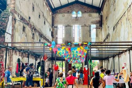 Feira criativa Caipora com pessoas e expositores em espaço com arquitetura antiga.