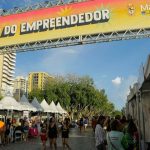 Feira de empreendedores em Ponta Negra, com barracas e pessoas caminhando.