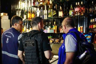 Fiscais em operação em estabelecimento, com bebidas alcoólicas em prateleiras.