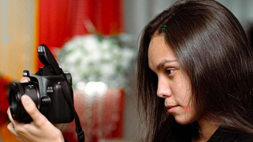 Fotógrafa segurando câmera EOS 400D, com detalhes em exposição sobre hip-hop amazonense.