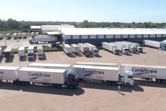 Frota de caminhões 'Combitrans' estacionados em pátio logístico, com foco em transporte e sustentabilidade na Amazônia.
