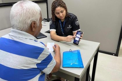 Funcionária da Amazonprev mostrando celular para segurado durante recadastramento.