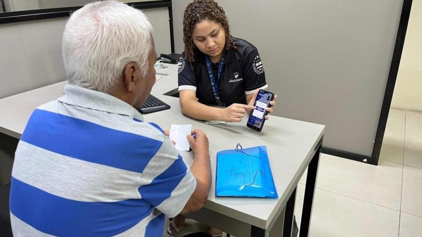 Funcionária da Amazonprev mostrando celular para segurado durante recadastramento.
