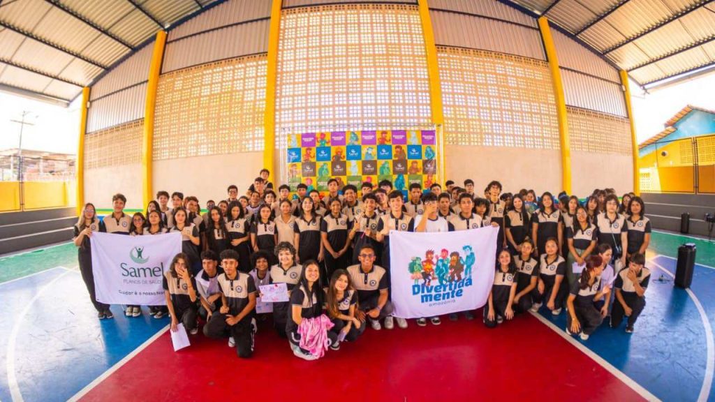 Grupo de alunos com faixas 'Samel Planos de Saúde' e 'Divertidamente'