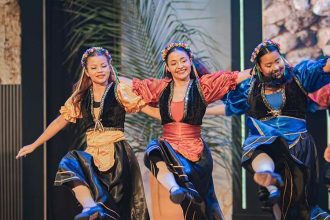 Grupo de dança se apresenta com trajes coloridos no Festival Cultural de Tabernáculos em Ponta Negra.