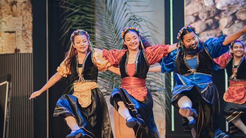 Grupo de dança se apresenta com trajes coloridos no Festival Cultural de Tabernáculos em Ponta Negra.