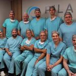 Grupo de médicos em centro cirúrgico, sorrindo para a câmera