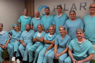 Grupo de médicos em centro cirúrgico, sorrindo para a câmera