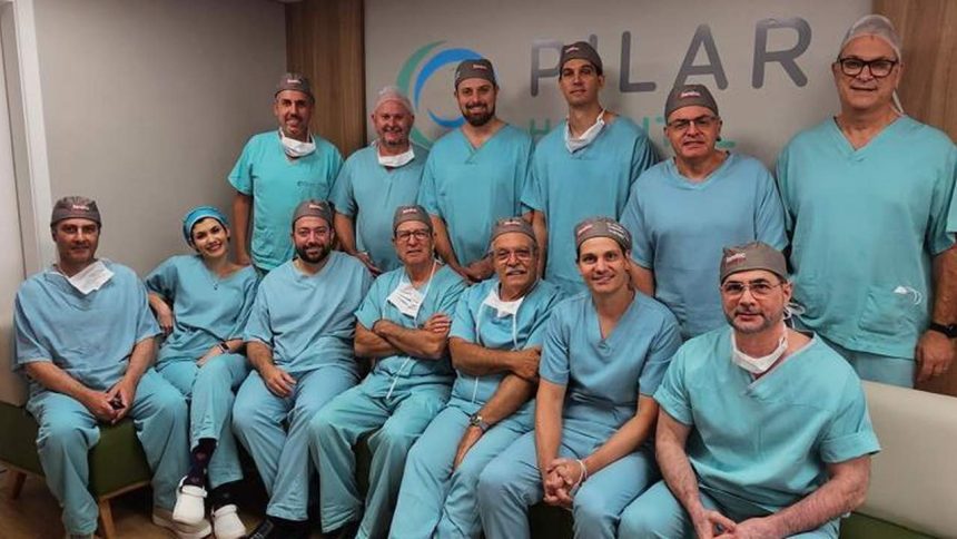 Grupo de médicos em centro cirúrgico, sorrindo para a câmera