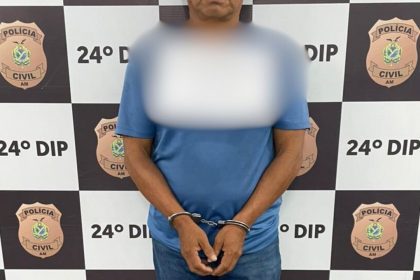 Homem algemado em frente a um fundo policial. Censura facial.