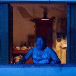 Homem assustado em janela com tela, cena do filme 'Mata-Gato'.