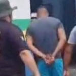 Homem preso sob custódia policial. Detido com as mãos algemadas.