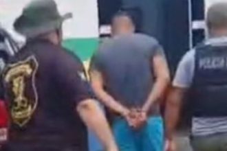 Homem preso sob custódia policial. Detido com as mãos algemadas.