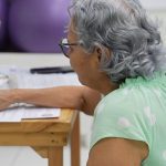 Idosa em atendimento na Defensoria Pública, utilizando computador.