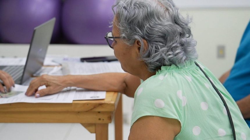 Idosa em atendimento na Defensoria Pública, utilizando computador.