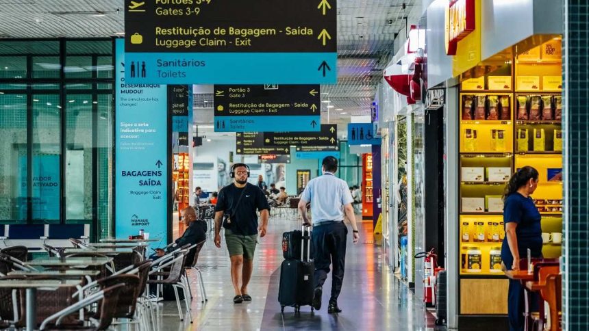 Interior de aeroporto com sinalização e pessoas andando.