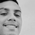 Jovem sorrindo em preto e branco.