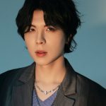 KISU, cantor coreano, em um retrato com fundo azul.
