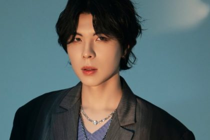 KISU, cantor coreano, em um retrato com fundo azul.