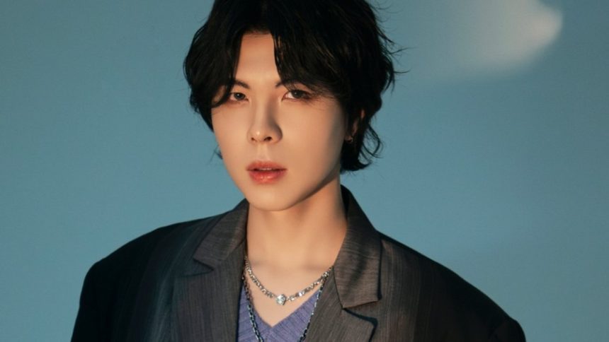 KISU, cantor coreano, em um retrato com fundo azul.