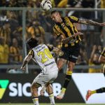 Lance de futebol com jogadores disputando a bola.