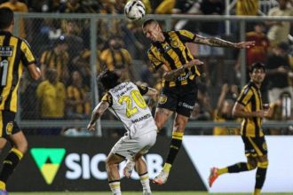 Lance de futebol com jogadores disputando a bola.