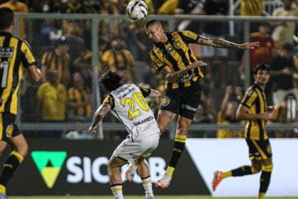 Lance de futebol com jogadores disputando a bola.